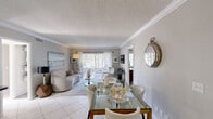 Located in Palm Beach Gardens, FL, this thoughtfully designed residence offers three bedrooms and four bathrooms across a single floor. The bright living room serves as the heart of the home, featuring crown molding, soft neutral tones, and sliding glass doors with vertical blinds that open to a private patio, filling the space with natural light and providing seamless indoor-outdoor connectivity.

The kitchen is efficiently laid out with white cabinetry, dark countertops, a classic tile backsplash, stainless steel appliances including a refrigerator, range, and built-in microwave, and light tile flooring — delivering both functionality and a clean aesthetic.

The primary bedroom is a comfortable retreat, complete with plush carpeting, a large window dressed with sheer curtains, and ample wall space. Additional bedrooms share a similar warm, carpeted ambiance, with one featuring a walk-in closet.

The four bathrooms are finished with white cabinetry, dark countertops, tile flooring, and well-lit vanity mirrors. One bathroom showcases a tub-shower combination with elegant diagonal tile surround. Throughout the residence, a cohesive neutral palette and consistent finishes create a calm, inviting atmosphere well-suited to Florida living.