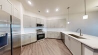 This well-appointed one-bedroom, one-bathroom residence in Spring, TX offers a thoughtfully designed single-floor layout that maximizes functionality and style. The kitchen is a standout feature, showcasing soft gray shaker-style cabinetry extending floor to ceiling, bright white subway tile backsplash, quartz countertops, and a full suite of stainless steel appliances including a range, over-the-range microwave, dishwasher, and side-by-side refrigerator with ice and water dispenser. A pendant light adds a refined finishing touch above the counter space. Wood-look plank flooring flows throughout the main living areas, lending warmth and visual continuity. The living area is open and bright, connected seamlessly to the kitchen. The bedroom offers comfortable proportions, plush carpet, a ceiling fan, and windows fitted with blinds that invite natural light and outdoor views. The bathroom features a walk-in glass-enclosed shower with tile surround and a clean, modern finish. A dedicated closet with built-in shelving and a hanging rod provides organized storage. Recessed lighting throughout ensures consistent illumination, and neutral wall tones create a clean, move-in-ready aesthetic throughout the space.