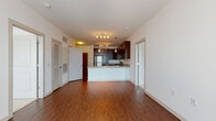 This single-floor unit offers a thoughtfully designed open-concept layout with distinct living and kitchen zones united by rich hardwood-style flooring. The living area provides generous space for entertaining, with neutral white walls and multiple doorways—including a louvered closet door—offering practical storage access.

The kitchen is a standout feature, equipped with dark espresso cabinetry extending to the ceiling, granite countertops, and a full suite of stainless steel appliances including a gas range, built-in microwave, and French door refrigerator. A peninsula with a breakfast bar separates the kitchen from the living space, and track and pendant lighting adds both task illumination and visual warmth.

Multiple bedrooms are finished with plush neutral carpeting and feature large windows that invite natural light. One bedroom includes a sliding glass door providing additional access to the outdoors.

The bathrooms are well-appointed, featuring dark vanity cabinetry, granite countertops, and tile flooring. The primary bathroom includes a dual-sink vanity with an expansive mirror and tall storage tower, while a secondary bathroom offers a tub-shower combination with white subway tile surround.