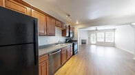 This three-story home offers a well-organized layout across three distinct levels, providing functional living spaces throughout. The ground floor houses an entrance, garage access, and basement areas, one of which is currently unfinished with exposed framing and concrete flooring, presenting a versatile opportunity for future customization or additional living space.

The main living level features a combined kitchen and living room that flows seamlessly together. The kitchen is appointed with rich, warm-toned wood cabinetry, dark granite-style countertops, and black stainless appliances, including a refrigerator, range, and dishwasher. The adjacent living room is bright and inviting, highlighted by a tile-surround fireplace, hardwood-style flooring, and a ceiling fan. A bathroom and hallway complete this level.

The upper floor is home to two bedrooms, including a generously sized primary bedroom with a tray ceiling, ceiling fan, carpeted flooring, and a natural light-filled window. Two closets with wire shelving systems provide ample storage. A dedicated laundry room with side-by-side washer and dryer hookups and overhead wire shelving adds everyday convenience. The three bathrooms feature tile flooring and wood-toned vanity cabinetry consistent with the home's overall design aesthetic.