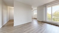 This 2-bedroom, 1-bathroom unit in Leamington, Ontario offers a practical and comfortable single-floor layout. Light-toned wood-look flooring flows consistently throughout the space, lending a clean and cohesive aesthetic to every room. The entrance leads into a thoughtfully organized floor plan that connects the living areas, bedrooms, kitchen, and hallways efficiently.

The living room is an open, airy space featuring a ceiling fan and a baseboard heating unit, with a window allowing natural light to fill the room. The neutral white walls and light flooring create a bright, welcoming atmosphere. An adjacent secondary living or dining area extends the usable space comfortably.

The galley-style kitchen is well-equipped with warm wood cabinetry, marble-patterned countertops, a stainless steel sink, and white appliances including a refrigerator and electric range. A doorway connects the kitchen directly to the rest of the unit for easy flow.

Both bedrooms are modest and functional, featuring the same light flooring, neutral wall tones, and white baseboard trim. The primary bedroom benefits from a window with a blind, allowing controlled natural light, while baseboard heating ensures year-round comfort.

The bathroom is finished in a clean, all-white palette with large subway tile surrounding a full soaker tub and shower combination, complemented by marble-look tile flooring. The overall unit presents a tidy, move-in-ready feel.