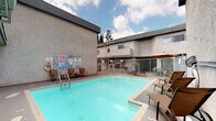Located in the heart of Sherman Oaks, California, this shared amenity space at 4620 Tilden Ave offers residents two key community features designed for convenience and relaxation. The centerpiece of the outdoor area is a generously sized swimming pool with clear, turquoise water, enclosed by a white metal security fence for safety. The pool deck is surrounded by multiple lounge chairs and additional seating arrangements, providing ample space for sunbathing and outdoor leisure. A shaded seating area with an umbrella and table offers a comfortable spot to relax out of the sun. The pool area is set within a courtyard framed by the surrounding multi-story stucco building, creating a semi-private and sheltered atmosphere open to the California sky. The second amenity is a bright, well-lit on-site laundry room, equipped with a row of coin-operated washing machines and dryers lining the walls. Natural light filters in through a window, keeping the space airy and functional. The clean, straightforward layout makes laundry tasks efficient and accessible. Together, these amenities reflect a practical and community-oriented design, well-suited to the sunny Southern California lifestyle.