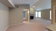 The Dogwood floor plan is a thoughtfully designed 2-bedroom, 1-bathroom residence that offers a comfortable and functional single-story layout. The spacious living room features vaulted ceilings, plush carpeting, and a tile-surround fireplace, creating a warm and inviting focal point. Natural light fills the room through a large window, while a sliding glass door provides easy access to the outdoors. The open-concept kitchen is appointed with rich dark cabinetry, granite-style countertops, black appliances including a range and built-in microwave, and wood-style flooring, all accessible via a convenient breakfast bar that connects to the living area. Both bedrooms are generously sized, each featuring ceiling fans, plush carpet, and ample natural light from large windows. One bedroom includes a walk-in closet with built-in shelving, providing excellent storage. The full bathroom showcases a granite-style vanity countertop, dark cabinetry, a large mirror, and stylish pendant lighting. Throughout the residence, neutral earth-tone walls, clean white trim, and consistent finishes create a cohesive and welcoming ambiance suited for everyday living.