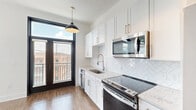 Located at 601 Indian St in the heart of Savannah, Georgia, this efficiently designed single-floor unit offers a thoughtfully arranged layout that maximizes every square foot. The kitchen serves as a centerpiece of the space, showcasing crisp white shaker cabinetry with brushed nickel hardware, a herringbone-patterned tile backsplash, stainless steel appliances including a range, microwave, dishwasher, and refrigerator, and a undermount sink beneath a modern pendant light. Black-framed French doors open to a private balcony, flooding the kitchen with natural light and offering views of the surrounding Savannah streetscape. Wide-plank hardwood-style flooring runs throughout, providing warmth and continuity. The main living area features striking black-framed arched windows that frame outdoor views while bathing the room in daylight. The bathroom is clean and contemporary, finished with wood-look flooring, a glass-enclosed shower, and a crisp white palette. Additional functionality is provided through a dedicated laundry area and utility room. A bold, dark three-panel entry door adds a sophisticated design accent. This unit blends modern finishes with classic Savannah character for a polished, move-in-ready space.