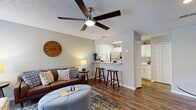 This single-floor residence offers a thoughtfully designed open-concept layout that seamlessly connects the living, dining, and kitchen areas. The living room is a welcoming space, highlighted by wood-look flooring, a ceiling fan, and textured ceilings. It comfortably accommodates a full seating arrangement and opens to a dedicated dining nook featuring a glass-top table and warm neutral walls.

The kitchen is efficiently designed with crisp white cabinetry, light quartz countertops, stainless steel appliances including a refrigerator, electric range, and over-the-range microwave, and a pass-through breakfast bar with barstool seating — ideal for casual dining and entertaining.

The bedroom is a restful retreat with plush carpet flooring, a ceiling fan, and generous closet space that includes a walk-in closet with shelving and an additional separate closet for added storage.

The bathroom is clean and modern, outfitted with a white vanity, quartz countertop, a large mirror with overhead lighting, and a shower-tub combination. Wood-look flooring extends into this space, maintaining a consistent aesthetic throughout.

Overall, the residence presents a cohesive, neutral color palette with modern finishes that create a bright, comfortable, and functional living environment.
