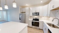 Located at 200 Brooklawn St in Farragut, TN, this well-appointed one-bedroom, one-bathroom residence offers a thoughtfully designed single-floor layout with modern finishes throughout. The open-concept kitchen and living area serves as the heart of the home, featuring crisp white shaker cabinetry, a marble-inspired tile backsplash, gleaming white quartz countertops, and a full suite of stainless steel Whirlpool appliances including a French door refrigerator, electric range with over-the-range microwave, and dishwasher. A central kitchen island provides additional prep and seating space, while stylish pendant lighting adds warmth overhead. Light wood-style flooring runs through the living and kitchen areas, complementing the bright, neutral color palette. The living room benefits from abundant natural light and a ceiling fan. The carpeted bedroom is a comfortable retreat, complete with its own ceiling fan, a window with exterior views, and access to a closet. The clean, modern bathroom features a glass-enclosed walk-in shower with subway tile surround, wood-style flooring, brushed nickel fixtures, and a white vanity. A utility room and additional closet round out the functional layout of this move-in ready Farragut residence.