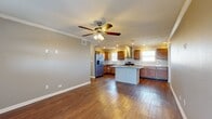 This single-story, 2-bedroom, 1-bathroom home offers a thoughtfully designed layout with a seamless blend of functional and aesthetic details. The open-concept living and kitchen area is anchored by rich hardwood flooring, crown molding, and ceiling fans with light fixtures, creating a bright and welcoming atmosphere. Natural light filters in through multiple windows, enhancing the airy feel of the space.

The kitchen is a standout feature, showcasing warm wood cabinetry, granite countertops, and a classic white subway tile backsplash. A center island provides additional prep space, while stainless steel appliances — including a gas range, dishwasher, and French door refrigerator — and a stainless steel wall-mounted range hood complete the culinary setup. A pantry adds convenient storage.

Both bedrooms are carpeted and finished with neutral tones, offering a comfortable retreat. Ceiling fans are present in each room. The spacious primary bedroom connects to well-sized closets with wire shelving systems for organized storage.

The bathroom is elegantly appointed with dual vessel sinks set on granite countertops, rich wood cabinetry, large mirrors, and tile flooring. The laundry area is conveniently accessible from within the bathroom. A hallway connects the main living spaces, completing this efficiently planned home.