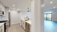 Located at 282 South Ave in Fanwood, NJ, this thoughtfully designed two-story residence offers 2 bedrooms, 3 bathrooms, a loft, and a private balcony across two well-proportioned floors. The main level sets a welcoming tone with an open-concept kitchen and living area anchored by a beadboard island, light cabinetry, subway tile backsplash, stainless steel appliances, and elegant black-and-gold pendant lighting. Light hardwood-style flooring flows throughout, complementing the crisp white walls and clean modern aesthetic. A dedicated mudroom entry features built-in beadboard paneling, gold coat hooks, an upper shelf, and a bench — a practical and charming transition space. The upper level hosts the generously sized primary bedroom, which opens directly onto the private balcony through floor-to-ceiling sliding glass doors topped with transom windows, flooding the space with natural light and outdoor views. A second bedroom features vaulted ceilings with exposed angles and a ceiling fan, adding architectural character. The loft level offers built-in shelving and an open railing staircase. Three bathrooms are finished with large-format tile, backlit mirrors, and refined vanities. Abundant closet storage, a pantry, and a utility room round out this well-appointed home.