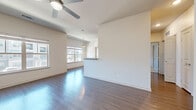 This single-floor, 2-bedroom, 2-bathroom unit offers a practical and well-designed layout suited for comfortable everyday living. The open-concept living and dining area is a standout feature, showcasing rich hardwood-style flooring, neutral walls, and a ceiling fan that enhances airflow and comfort. Multiple large windows flood the space with natural light while offering views of the surrounding neighborhood. The living area flows seamlessly into the kitchen, which is equipped with dark espresso cabinetry, black appliances including a refrigerator, range, and microwave, and light-colored countertops with a convenient breakfast bar. A secondary entry door in the kitchen area adds accessibility. The primary bedroom is a spacious retreat featuring plush carpet, a ceiling fan, and a window for natural light. The second bedroom, also carpeted, includes its own ceiling fan and window with outdoor views. Both bathrooms are finished with neutral large-format tile surrounds in the tub-shower combinations, complemented by wood-tone vanities and hardwood-style flooring. Three closets throughout the unit provide generous storage. The clean, contemporary palette of whites and warm neutrals creates a bright, cohesive ambiance throughout.