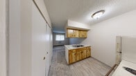 Located at 6 Hidden Valley Dr in Toledo, Ohio, this single-floor, one-bedroom, one-bathroom unit offers a practical and efficient layout. The living room features neutral-toned carpet, a textured ceiling, and a closet with bifold doors, creating a clean and functional space. Adjacent to the living area, the kitchen is designed with an open, pass-through configuration that allows visibility across the main living space. It is equipped with warm wood-toned cabinetry, a coil-burner electric range, a refrigerator, a double-basin sink with countertop workspace, and tile-style flooring. The overhead cabinetry provides ample storage, and a ventilation hood is positioned above the range. A hallway connects the main living areas to the bedroom, which features carpet flooring, a large double bifold closet, a window with blinds that brings in natural light, a baseboard heater, and direct access to the bathroom. The bathroom includes a clean, white tub and shower surround with a built-in shelf niche. Throughout the unit, baseboard heating units provide climate control, and the neutral color palette creates a cohesive, move-in ready environment. Three closets across the unit offer notable storage capacity for its size.