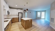Located at 22 Mount Carmel Way in Worcester, MA, this thoughtfully designed one-bedroom, one-bathroom residence offers a contemporary open-concept layout with consistent light hardwood flooring that runs throughout the entire space, creating a cohesive and bright atmosphere.

The combined kitchen and living area serves as the centerpiece of the residence. The kitchen is outfitted with a full suite of stainless steel appliances, including a refrigerator, stove, microwave, and dishwasher. White upper cabinetry contrasts elegantly with warm wood-toned lower cabinets, complemented by a white tile backsplash. A central island with a white countertop and matching wood-grain base provides additional prep space and is accented by stylish pendant lighting overhead. The open living area benefits from natural light through large windows and access to an exterior door.

The bedroom is a well-proportioned, quiet retreat with neutral-toned walls, a large window overlooking the surrounding building exterior, and continuity of the hardwood flooring. A dedicated closet provides practical storage.

The bathroom features a wood-toned vanity with ample drawer storage, a wide mirror with above-mirror lighting, and a clean, minimalist design consistent with the modern aesthetic found throughout the space.