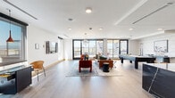 The View Lounge & View Terrace at 1900 S Acoma St in Denver, Colorado is a thoughtfully designed communal space that seamlessly blends sophisticated interiors with an inviting outdoor terrace. The open-plan lounge is finished with wide-plank hardwood flooring, crisp white walls, and recessed lighting complemented by statement pendant fixtures, including a striking globe chandelier that anchors the central gathering area. Large floor-to-ceiling glass doors flood the space with abundant natural light and frame panoramic views of the Denver cityscape and surrounding landscape. The living area features a curated mix of tufted leather sofas, bold accent chairs, and layered rugs, creating a warm yet contemporary atmosphere. A full-size pool table serves as a recreational centerpiece, while a sleek bar counter with a dramatic dark marble surface and geometric teal tile accent wall provides a casual dining and social hub with swivel bar seating. A dedicated dining zone with a dark table and modern chairs adds further versatility. The adjoining outdoor terrace showcases a pergola-covered lounge with a built-in grill station, decorative laser-cut panels, and alfresco dining seating, ideal for outdoor entertaining with open sky views.