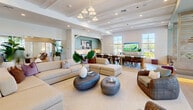 Located at 6026 Whitaker Rd in Naples, FL, this single-story clubhouse facility offers a generously sized, thoughtfully designed community space that blends modern coastal aesthetics with functional versatility. Light-toned hardwood flooring runs throughout, complementing white walls, exposed wood ceiling beams, and coffered ceilings that lend warmth and architectural character across the entire floor plan.

The welcoming entry foyer features glass doors, tall ceilings, and a reception desk, setting an organized and professional tone. The expansive main lounge areas are defined by abundant natural light pouring in through large floor-to-ceiling windows and glass doors that open to outdoor views of lush Florida landscaping. Multiple seating arrangements, statement pendant chandeliers, and flat-screen televisions create distinct zones for lounging, socializing, and entertainment.

A fully appointed kitchen with sage-green cabinetry opens seamlessly to a formal dining area with a long communal table, ideal for gatherings. A secondary lounge zone features teal accent walls, layered seating, and direct outdoor access via wide glass doors.

The private conference room stands out with a botanical tropical mural, a round table, a mounted display screen, and a sculptural overhead pendant light — offering an intimate and distinctive meeting environment. A dedicated office and closet round out the functional spaces within this well-appointed facility.