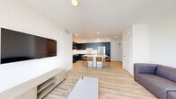 Located at 2555 Research Park Dr in Davis, CA, this modern multi-bedroom unit offers a thoughtfully designed single-level layout accommodating six bedrooms and three bathrooms. The open-concept living, dining, and kitchen area serves as the heart of the home, finished with light hardwood-style flooring that flows seamlessly throughout. The kitchen is a standout feature, showcasing bold navy cabinetry extending floor to ceiling, white quartz countertops, a white subway tile backsplash, and a full suite of stainless steel appliances. A central island with seating provides an ideal space for dining and gathering. The living area is bright and airy, with a wall-mounted TV, sliding glass doors, and access to a private balcony with outdoor views. Each bedroom is efficiently laid out with clean white walls, hardwood-style floors, and ceiling fans or ample natural light; select rooms include closets with built-in rods. The three bathrooms mirror the home's modern aesthetic, featuring navy vanities with white quartz countertops, large mirrors, and white tile shower-tub combinations with brushed nickel fixtures. A dedicated laundry area and hallway add to the unit's functional design, making this a well-appointed space suited for shared living.