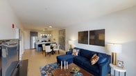Located at 1 St Mary's Convent in Peekskill, NY, this thoughtfully designed one-bedroom, one-bathroom residence offers a seamless blend of modern finishes and comfortable living. The open-concept layout connects the living, dining, and kitchen areas into one cohesive space, bathed in natural light and anchored by warm wood-tone flooring throughout.

The living area is generously proportioned, featuring large sliding glass doors that lead to a private balcony with expansive views of the surrounding landscape. The kitchen is a standout, boasting a large center island with crisp white countertops, a stainless steel sink, and pendant lighting overhead. Dark cabinetry on the lower units contrasts stylishly with white upper cabinets, while stainless steel appliances — including a refrigerator, range, and microwave — complete the contemporary look.

The bedroom is a calm and well-lit retreat, with windows framing outdoor views, a ceiling fan, and ample space for a full furniture arrangement. Natural light filters through sheer curtains, creating a serene atmosphere. The bathroom features large-format tile flooring, a dark wood vanity with a clean sink basin, and a well-lit mirror, offering a clean and functional design. An in-unit washer and dryer add everyday convenience to this well-appointed residence.