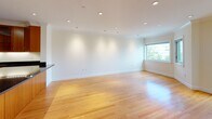 Located at 146–166 Marion St in Brookline, MA, this single-floor residence is designed with a clean, contemporary aesthetic and thoughtful layout. Warm hardwood flooring flows consistently throughout the living spaces, contributing to a cohesive and inviting atmosphere.

The open-concept living and dining area is generously proportioned, featuring recessed lighting and crown molding that add a refined architectural touch. Large windows allow natural light to fill the space while offering views of the surrounding Brookline neighborhood, including mature trees and nearby buildings.

The kitchen is well-appointed and partially open to the main living area, anchored by rich warm-toned wood cabinetry paired with sleek black granite countertops. Glass-front upper cabinets add visual depth, while stainless steel appliances—including a refrigerator, microwave, and range—complete the functional setup.

The bedroom areas continue the hardwood flooring and crown molding details, maintaining a consistent design language. One bedroom features access to a walk-in closet, providing ample storage.

The bathroom is finished with light travertine-style tile flooring, white cabinetry with stone countertops, a large vanity with mirror, and a combined tub and shower enclosed by glass doors, offering a clean and polished feel throughout.