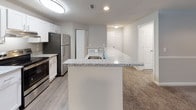 This single-floor residence at 8810 Autumn Woods Dr in Raleigh, NC offers a well-designed layout with a cohesive, neutral color palette throughout. The kitchen serves as a functional centerpiece, featuring white shaker-style cabinetry, granite countertops, stainless steel appliances including a refrigerator and range, and a peninsula with an integrated sink — ideal for both meal prep and casual dining. The kitchen flows seamlessly into the living area, which is finished with plush wall-to-wall carpet and windows that invite natural light. The bedrooms are generously sized, each carpeted and featuring windows with blinds that provide both light and privacy. One bedroom includes access to a spacious walk-in closet outfitted with multi-tiered wire shelving for ample storage. The bathrooms are tastefully appointed with white cabinetry, granite-topped vanities, brushed nickel hardware, and wood-look vinyl flooring, lending a clean and modern aesthetic. A second bathroom mirrors these finishes, maintaining design consistency throughout the home. The overall ambiance is bright, clean, and move-in ready, with practical finishes that balance style and durability across every room.