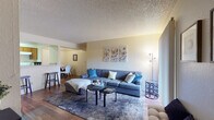 Located at 7300 N Mona Lisa Rd in Tucson, Arizona, this single-floor residence offers a well-organized layout with comfortable living spaces throughout. The living room serves as the heart of the home, featuring rich hardwood-style flooring, a textured ceiling, a tile-surround fireplace, and sliding glass doors that open to a private balcony with outdoor views, allowing natural light to fill the space. The open flow connects the living area to a dining space and galley-style kitchen, which is equipped with warm wood cabinetry, white appliances including a dishwasher, range, and refrigerator, along with ample counter space and an in-unit washer and dryer closet. The residence includes multiple bedrooms, each carpeted and fitted with ceiling fans for comfort. The primary bedroom features a window with vertical blinds and generous closet space, while a second bedroom accommodates versatile use with its flexible layout. Two bathrooms serve the home, each featuring wood-toned vanity cabinetry, light countertops, and hardwood-style flooring. The overall ambiance is bright and neutral, with warm beige tones and natural light creating an inviting atmosphere throughout this Tucson residence.