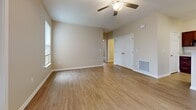 Located at 330 Cunningham Lane in Clarksville, Tennessee, this single-story, three-bedroom, two-bathroom home offers a well-organized and functional layout. The open living room features warm hardwood-style flooring, a ceiling fan with light fixture, and French doors flanked by windows that invite abundant natural light and outdoor views. The kitchen is equipped with rich, dark wood cabinetry, a peninsula with light-toned countertops, and black appliances, flowing seamlessly into the living area. A second living space or dining area also features hardwood-style flooring, a ceiling fan, and a closet, providing versatile use. The generously sized primary bedroom is carpeted and includes a ceiling fan, a window for natural light, and a large walk-in closet outfitted with wire shelving systems. Additional bedrooms are carpeted and well-proportioned, each with closet access. The three closets throughout the home, including walk-in designs, offer abundant storage. Both bathrooms feature wood-look tile flooring and dark wood vanities with light countertops; one includes a shower/tub combination, while the other presents a more open layout. Neutral, warm beige tones throughout create a cohesive and inviting ambiance across the entire home.
