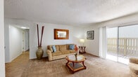 Located at 7887 E Uhl St in Tucson, Arizona, this single-floor residence offers a well-organized layout designed for comfortable everyday living. The living room serves as the heart of the home, featuring warm carpeted flooring, a textured ceiling, and a sliding glass door that opens to a private outdoor patio, allowing natural light to fill the space. The living area flows seamlessly into a separate dining area, which is outfitted with a ceiling fan for year-round comfort. The galley-style kitchen features rich wood cabinetry, light countertops, a double-basin stainless steel sink, and wood-look flooring, providing a functional and efficient cooking space. Two well-proportioned bedrooms offer plush carpet, natural light from sliding windows, and textured ceilings, creating a restful atmosphere. The primary bedroom is notably spacious, offering ample room for furnishings. The home includes two bathrooms: one featuring a walk-in shower with tile surround and wood-look parquet flooring, and the other offering a full tub-shower combination with white tile walls. Throughout the residence, a neutral color palette and clean finishes contribute to a bright, cohesive interior that is both practical and inviting.