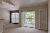 Located at 2330 Montgomery Park Blvd in Conroe, Texas, this single-floor unit offers a practical and comfortable layout designed for everyday living. The open-concept living and dining area features soft carpeting and connects seamlessly to the kitchen via a breakfast bar peninsula. The kitchen is laid out in a galley style, equipped with white cabinetry, granite-style countertops, a full suite of white appliances including a refrigerator, electric range, and microwave, and durable hardwood-style flooring that extends throughout the wet areas. The living area benefits from vaulted ceilings and access to a private balcony through sliding glass doors, allowing natural light to fill the space and offering views of surrounding greenery. Built-in shelving beside the balcony door provides convenient storage and display space. The bedrooms are carpeted and each features a ceiling fan with light fixture, providing comfort and ventilation. The full bathroom is clean and functional, featuring a tiled tub and shower combination, wood-style flooring, a toilet, and a vanity with granite-style countertops and ample overhead shelving. Neutral tones throughout the unit create a bright, cohesive aesthetic that is easy to personalize.