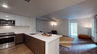Located at 2520 Telegraph Ave in Oakland, CA, this single-floor unit offers a thoughtfully designed open-concept layout that seamlessly connects the kitchen and living areas. The kitchen is a standout feature, showcasing two-tone cabinetry with white upper cabinets and warm walnut-finished lower cabinets, complemented by a white quartz countertop that extends into a peninsula with bar seating. Stainless steel appliances, including a refrigerator, range, and microwave, add a polished, contemporary feel, while wood-look flooring throughout the main living area enhances warmth and cohesion.

The living area provides a comfortable, open space with clean white walls and recessed lighting. The bedroom features plush carpeting and large windows that bring in natural light and offer views of the surrounding urban environment, including glimpses of a shared outdoor deck area. The bathroom is finished with a full soaking tub and shower combination, white surround panels, and wood-look flooring that ties back to the rest of the unit. Overall, the space presents a clean, modern aesthetic well-suited to contemporary urban living in the heart of Oakland.