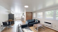 Located at 1231 S Allen Street in State College, PA, this well-designed 3-bedroom, 2-bathroom single-floor unit offers a comfortable and functional layout. The open-concept living and kitchen area serves as the heart of the home, highlighted by warm light wood flooring throughout, crisp white walls, and an eye-catching exposed brick column that adds architectural character. The living room features multiple windows that invite abundant natural light and provide outdoor views, creating a bright and welcoming atmosphere. The kitchen is outfitted with white shaker cabinetry, light stone countertops, and stainless steel appliances, with space for a small dining table nearby. Each of the three bedrooms is thoughtfully sized, featuring natural light from windows and ample closet space — with six closets spread throughout the unit. The bathrooms are clean and modern, with white tile surround tub-shower combinations and stone-top vanities. A dedicated laundry room with a full washer and dryer adds everyday convenience. Two balconies extend the living space outdoors, and a hallway connects the private bedroom wing seamlessly to the main living areas. The overall aesthetic is clean, modern, and move-in ready.