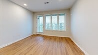Located at 1414 4th Ave S in Nashville, TN, this well-appointed 2-bedroom, 2-bathroom residence offers a thoughtfully designed single-level layout with modern finishes throughout. The open-concept living, dining, and kitchen area serves as the heart of the home, anchored by a large center island with a granite-style countertop, matte black faucet, and eye-catching sage green pendant lights. The kitchen features warm wood cabinetry, dark lower cabinets, a classic tile backsplash, and stainless steel appliances. Large windows flood the living area with natural light and offer views of the surrounding neighborhood. The primary bedroom is a generous retreat with hardwood-style flooring, direct outdoor access, and a spacious walk-in closet with wire shelving. Its en-suite bathroom showcases a dual-sink vanity with dark cabinetry, a soaking tub with white subway tile surround, a separate glass-enclosed shower, and light wood flooring. The second bedroom features plush carpeting, a bright window, and its own walk-in closet. Additional highlights include a laundry room, utility room, and ample storage with four closets total, making this a highly functional and stylish Nashville home.