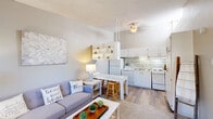 Located at 9300 Montana Ave in El Paso, TX, this one-bedroom, one-bathroom unit offers a thoughtfully organized single-floor layout that maximizes every square foot. The open-concept living and kitchen area serves as the heart of the home, where wood-style flooring, neutral tones, and a ceiling fan create a bright and welcoming atmosphere. The kitchen is well-equipped with white cabinetry, a tile backsplash in subtle earth tones, a full-size refrigerator, dishwasher, electric range, and a built-in breakfast bar with seating — an efficient and functional cooking and dining space. A set of open shelves adds a decorative touch between the living and kitchen areas. The living area comfortably accommodates a seating arrangement with natural light filtering in through the windows. The bedroom is carpeted for comfort, featuring a wall-mounted AC unit and a window with outdoor views, and it connects openly to the living space for a seamless flow. A dedicated closet provides storage within the bedroom. The bathroom includes a full tub and shower combination with classic white and tan tile accents, a vanity mirror, and clean, neutral finishes throughout. This unit offers a practical and comfortable living environment in a convenient El Paso location.