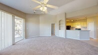 Located in East Lake, FL, this single-floor, 2-bedroom, 2-bathroom home offers a well-designed open-concept layout with a comfortable and functional flow throughout. The living room is generously sized, featuring soft carpeting, a ceiling fan with light kit, a built-in shelving nook, and large sliding glass doors that invite abundant natural light and provide outdoor views. A dedicated ceiling-mounted track lighting system adds additional illumination to the space.

The kitchen connects seamlessly to the living area via a peninsula breakfast bar with a countertop sink. It is equipped with cream-toned cabinetry, open display shelving, tile flooring, black appliances including a refrigerator with ice maker and a range, and direct access to an in-unit laundry area.

The primary bedroom is spacious and bright, with vaulted ceilings, a ceiling fan, large windows, and a sliding glass door to the outdoors. It includes a walk-in closet for ample storage. The second bedroom is well-proportioned with a ceiling fan, carpeted floors, and a window for natural light.

Both bathrooms are finished with tile flooring, vanity cabinetry, and neutral countertops. The home also benefits from three closets total, providing excellent storage throughout the residence.