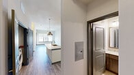 Located at 916 Norwood St in Fort Worth, Texas, this well-designed 2-bedroom, 2-bathroom residence offers a thoughtfully arranged single-level floor plan. Wood-look flooring flows throughout the main living areas, lending a cohesive and modern aesthetic. The open-concept kitchen serves as a central hub, anchored by a center island with a sink and light stone countertops, complemented by gray cabinetry, stainless steel appliances, and stylish pendant lighting. The kitchen connects seamlessly to the living area, creating an ideal space for everyday living and entertaining. The primary bedroom is a comfortable retreat, carpeted for warmth, while the second bedroom features wood-look flooring and a wide window with roller shades that allows natural light to fill the room. The primary bathroom impresses with a double-sink vanity topped with stone counters, dark cabinetry, a large mirror, and a glass-enclosed walk-in shower with tile surround. The second bathroom features a single-sink vanity with matching stone countertops, dark wood cabinetry, an overhead cabinet, and a framed mirror. A hallway and closet provide practical storage solutions, rounding out this clean, contemporary residence.