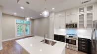 Located at 500 West Trade Street in Uptown Charlotte, NC, this one-bedroom, one-bathroom residence offers a well-designed single-floor layout with a thoughtful mix of modern finishes and functional living spaces. Wood-style plank flooring runs throughout the living and bedroom areas, complementing the neutral, warm-toned walls that create a clean and cohesive aesthetic.

The kitchen is a standout feature, showcasing a two-tone design with crisp white upper cabinetry — including glass-front accent doors — paired with dark lower cabinets. Stainless steel appliances include a gas range, built-in microwave, French door refrigerator, and dishwasher. A large center island with white quartz countertops and an under-mount sink serves as both a prep and gathering space, illuminated by globe pendant lights overhead.

The spacious primary bedroom offers generous proportions, a ceiling fan, and ample natural light. The bathroom features light tile flooring, a dark vanity with white countertops, and a glass-enclosed shower. A dedicated closet provides additional storage.

The residence also offers views of a lush, landscaped courtyard garden shared within the building community, adding a welcome touch of greenery to the urban setting. The overall design balances contemporary style with comfortable, practical living in the heart of Charlotte.