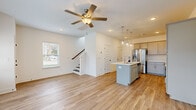 Located at 212 Hays Ridge Lane in Nashville, TN, this two-story home offers a clean, modern design with a cohesive aesthetic carried throughout both levels. The main floor centers on an open-concept living and kitchen area, where light wood-style flooring, crisp white walls, and a ceiling fan create a bright, welcoming atmosphere. Multiple windows allow natural light to fill the space, with views of the surrounding neighborhood. A front entrance door with sidelight windows adds additional brightness to the living area.

The kitchen is well-appointed with gray shaker-style cabinetry, white countertops, and a full suite of stainless steel appliances, including a refrigerator with ice maker, electric range, microwave, and dishwasher. A central island with a built-in sink and pendant lighting above serves as a functional focal point. A staircase with a wood handrail connects the main floor to the upper level.

Upstairs, the bedrooms continue the light wood-style flooring and neutral palette. One bedroom features vaulted ceilings and a ceiling fan. The primary suite includes an en-suite bathroom with a glass-enclosed shower, gray vanity cabinetry, and access to a spacious walk-in closet with wire shelving. A dedicated laundry room with full-size washer and dryer completes the upper level.