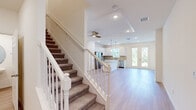 This two-story home offers a well-organized layout across two levels, with the main floor housing the combined kitchen and living area, and the upper floor dedicated primarily to the three bedrooms, three bathrooms, hallway, closet, and laundry room. The main level greets visitors with an open-concept living and kitchen space finished with light hardwood flooring and recessed lighting. A ceiling fan adds functionality, while French doors invite natural light and outdoor views. The staircase, featuring a white-painted banister and carpeted treads, connects both floors seamlessly.

The kitchen is outfitted with white shaker cabinetry, quartz countertops, a tile backsplash, stainless steel appliances including a range, microwave, refrigerator, and dishwasher, and a central island for added workspace.

Upstairs, the generously sized primary bedroom includes a tray ceiling detail and an en-suite bathroom featuring a tiled walk-in shower with sliding glass doors and a quartz vanity. Additional bedrooms offer light hardwood flooring and built-in closets. A dedicated laundry room with a full-size washer and dryer, along with a spacious walk-in closet with wire shelving, complete the upper level.