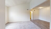 Located at 6200 S Campbell Ave in Tucson, Arizona, this single-floor unit offers a well-organized layout with a clean, neutral aesthetic throughout. The living area immediately stands out with its dramatic vaulted ceilings that lend a sense of openness and airiness to the space. Plush carpeting covers the living and bedroom areas, while wood-look vinyl flooring flows through the kitchen and bathroom, creating a practical and cohesive design. The transition between the carpeted and hard-surface zones is clearly defined, adding visual interest to the open layout.

The kitchen is equipped with warm-toned wood cabinetry, dark granite-style countertops, and a full suite of white appliances including an electric range, dishwasher, and refrigerator. A range hood is positioned above the stove, and ample cabinet storage is provided both above and below the countertops.

The bedrooms are bright and comfortable, each featuring plush carpet, vertical blinds, and windows or sliding glass doors that allow natural light to fill the rooms. One bedroom includes access to an outdoor area through a sliding glass door. The bathroom is finished with matching wood cabinetry, a dark countertop vanity with a single sink, a tub-shower combination, and wood-look flooring, maintaining consistency with the rest of the unit.