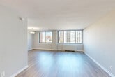 Located at 1401 Blair Mill Rd in Silver Spring, Maryland, this one-bedroom, one-bathroom residence offers a well-organized floor plan across a single level. The combined living and dining area is the heart of the home, featuring light wood-style flooring, neutral gray walls, and a wall of large windows that flood the space with natural light and frame sweeping urban views of the Silver Spring skyline. A pendant chandelier adds a refined accent to the dining area.

The galley-style kitchen is efficiently designed with rich dark wood cabinetry, light countertops, a tile mosaic backsplash, and a full suite of stainless steel appliances including a gas range, built-in microwave, and refrigerator. A pass-through opening connects the kitchen to the living area, enhancing the open feel.

The generously sized primary bedroom is carpeted for comfort and features large windows with continued city views and a baseboard heating unit. Three closets throughout the unit provide ample storage. A hallway connects the main living spaces to the bedroom and full bathroom. The overall aesthetic is clean, modern, and move-in ready, offering a functional urban living environment in a well-positioned Silver Spring location.