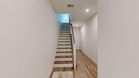 Located at 20 Parsippany Rd in Whippany, NJ, this contemporary three-story home offers a well-organized layout distributed across a ground-level entry floor, a main living level, and an upper bedroom floor. The entry level features light hardwood flooring, recessed lighting, and a staircase with wood-tread steps and white risers that connects all three floors.

The main living level hosts an open-concept kitchen, dining, and living area filled with natural light from large windows. The kitchen features gray cabinetry, a white quartz peninsula with bar seating, subway tile backsplash, stainless steel appliances, and pendant lighting. The dining area includes a glass door providing outdoor views and access, while the living room benefits from corner windows that bring in abundant natural light.

The upper floor contains both bedrooms, three full bathrooms, and a dedicated laundry room. The generously sized primary bedroom features soft carpeting, a double-door closet, and a private ensuite with a glass-enclosed walk-in shower and tile flooring. The second bedroom mirrors the clean, bright aesthetic with its own double-door closet and natural light. A walk-in closet with wire shelving provides additional storage. The laundry room includes a window, tile flooring, and space for a full-size washer and dryer.