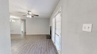 This single-story, 2-bedroom, 2-bathroom home offers a functional and modern layout across its entirety. The open-concept living, dining, and kitchen area serves as the heart of the home, featuring wood-look laminate flooring, neutral gray walls, and a textured ceiling throughout. The living room is highlighted by a striking tile-surround fireplace with a classic white mantle, a ceiling fan with integrated lighting, and French doors that invite natural light and provide outdoor access. The kitchen is well-equipped with slate-gray cabinetry, granite countertops, stainless steel appliances, a mosaic tile backsplash, and a peninsula with pendant lighting — seamlessly connecting to the dining area, which is illuminated by a chandelier. Both bedrooms are comfortably sized, each with ceiling fans, wood-look flooring, and access to closets, including a spacious walk-in closet in the primary bedroom. The bathrooms feature granite vanity countertops, gray cabinetry, and a tiled tub-shower combination. Three total closets — including a pantry — provide generous storage throughout. The home presents a cohesive, updated aesthetic with consistent finishes across all rooms.