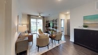 The B3 floor plan is a thoughtfully designed two-bedroom, two-bathroom residence that combines modern aesthetics with functional living spaces across a single floor. Rich wood-style flooring flows throughout the main living areas, anchoring the open-concept layout.

The kitchen is a standout feature, showcasing two-tone cabinetry with white upper cabinets and wood-finish lower cabinets, granite countertops, a grey tile backsplash, stainless steel appliances, and a tray ceiling with accent lighting. Ample storage is provided through a full-height pantry cabinet and open shelving.

The living room is bright and welcoming, with large sliding glass doors that open to a private balcony with outdoor views, complemented by a ceiling fan and recessed lighting. The dining area connects seamlessly to both the kitchen and living room.

Each bedroom offers plush carpeting, ceiling fans, and generous natural light from large windows. The primary bedroom includes an en-suite bathroom featuring a granite-topped vanity, wood-finish cabinetry, dark hardwood-style flooring, and a glass-enclosed shower. A spacious walk-in closet with multi-level shelving and hanging rods provides extensive storage. The second bathroom features a dual-sink vanity with granite countertops and a soaking tub with tiled surround.