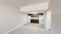 Located in Jupiter, FL, this one-bedroom, one-bathroom unit offers a functional and efficient single-floor layout. The open-concept kitchen and living area serves as the heart of the home, featuring wood-look tile flooring that transitions seamlessly to plush carpeting in the living space. The kitchen is equipped with dark espresso cabinetry, a white refrigerator, electric range, and a sink, all illuminated by a skylight overhead that brings in natural light. Crown molding and a textured ceiling add a subtle architectural detail throughout.

The bedroom is a comfortable, carpeted retreat featuring a ceiling fan with light fixture, a window with blinds offering natural light and outdoor views, and access to closet space. Three closets total are distributed throughout the unit, providing generous storage. A hallway connects the main living areas to the bedroom and bathroom, which features dark wood cabinetry with a white countertop vanity, a toilet, and a shower-tub combination with a curtain rod.

A dedicated utility room houses the water heater and additional mechanicals. Neutral gray walls, consistent trim work, and wood-look flooring in the entry area round out this well-organized and practical unit in Jupiter, Florida.