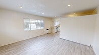 Located at 6565 Trigo Rd in Goleta, California, this thoughtfully designed single-floor unit offers a clean, modern aesthetic with light-toned wood-look flooring that flows seamlessly throughout the entire space. The open-concept kitchen and living area maximizes the layout efficiently, creating a bright and airy environment enhanced by multiple windows dressed with horizontal blinds that invite natural light. The kitchen is well-appointed with crisp white cabinetry, light stone-look countertops, stainless steel appliances including a gas range, dishwasher, and refrigerator, along with recessed lighting overhead. A peninsula-style counter provides a natural transition between the kitchen and the open living area, which features a textured ceiling and recessed lighting. Windows offer views of the surrounding greenery, adding a refreshing outdoor connection. The bathroom is a standout feature, showcasing elegant marble-look tile walls within a glass-enclosed shower, wood-look tile flooring, a sleek vanity with white countertop, and recessed lighting — all combining to create a polished, spa-inspired feel. The overall ambiance of this unit is bright, clean, and contemporary, making efficient and attractive use of its compact footprint.