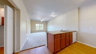 This 1-bedroom, 1-bathroom unit offers a practical and comfortable single-floor layout. The open-concept living and kitchen area forms the heart of the space, where wood-look flooring in the kitchen transitions to soft carpet in the living area. The kitchen features a peninsula with a laminate countertop and double sink, warm-toned wood cabinetry, and a full suite of white appliances including a refrigerator, electric range, microwave, and dishwasher. A ceiling fan with light fixture overhead and a large window bring natural light and airflow into the connected living area, which offers pleasant outdoor views of greenery.

The bedroom is a well-sized, carpeted room with a ceiling fan, large window with natural views, and neutral walls that create a calm atmosphere. An adjacent walk-in closet provides ample storage with built-in shelving and hanging rods. The bathroom is outfitted with hardwood-style flooring, a wide vanity with white cabinetry and a mirror, a standalone shower, and a toilet. A hallway connects the main living areas, completing this efficiently organized and move-in ready floor plan.