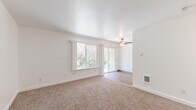 This single-floor, 3-bedroom, 1-bathroom home offers a clean and functional layout with a bright, welcoming atmosphere throughout. The living area is a standout space, featuring plush wall-to-wall carpeting, crisp white walls, and a ceiling fan overhead. Large windows flood the room with natural light, while a sliding glass door provides direct outdoor access and views of surrounding greenery, creating a seamless indoor-outdoor connection. A wall-mounted heating unit ensures year-round comfort.

Each of the three bedrooms continues the carpeted flooring and neutral white palette. The primary bedroom is a comfortable, well-proportioned retreat, while the secondary bedrooms benefit from natural light provided by windows overlooking lush trees. Several bedrooms include built-in closets with sliding doors, shelving, and hanging rods for practical storage. Wall-mounted heating units are present in multiple rooms.

The bathroom is tastefully finished with wood-look flooring, a white vanity with a quartz-style countertop, a black-framed mirror, and a full tub-and-shower combination accented with warm beige tile surround and chrome fixtures.

A connecting hallway ties the rooms together, completing a cohesive, efficiently designed home that balances simplicity with functional comfort throughout.