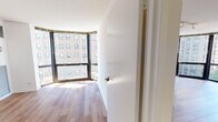 Situated on North Dearborn Street in Chicago's prestigious Gold Coast neighborhood, this well-appointed unit offers a thoughtfully designed single-floor layout filled with natural light. The living area is a standout, featuring rich wood-style flooring and sleek track lighting mounted on a textured ceiling, creating a clean, modern aesthetic. Expansive floor-to-ceiling curved windows wrap around the corner of the space, flooding the interior with sunlight and providing open views of the surrounding Chicago cityscape.

The bedroom continues the bright, airy feel with its own set of large curved windows and a mirrored sliding-door closet that reflects natural light throughout the room. A built-in HVAC vent ensures year-round comfort.

The kitchen is equipped with warm wood-toned cabinetry, dark countertops, a stainless steel sink, and black appliances including a full-size refrigerator and dishwasher. White tile flooring anchors the space with a clean, practical finish.

The bathroom is finished with white tile flooring and tub surround, a wood-accented vanity, and a full soaking tub with shower. The overall design of the space balances contemporary finishes with functional living, making it a well-rounded urban residence in one of Chicago's most sought-after neighborhoods.
