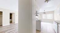 Located on N Doheny Drive in Beverly Hills, this single-story unit offers a clean, neutral palette throughout, with light-toned walls and consistent light wood laminate flooring connecting the main living areas. The open living and dining area is generously proportioned, allowing for flexible furniture arrangements. A sliding glass door draws in natural light and provides access to an outdoor area, while a contemporary chandelier adds a subtle design accent overhead.

The galley-style kitchen is efficiently laid out, featuring white cabinetry, dark granite countertops, a white double sink, matching white appliances including an electric range, and a built-in microwave. Tile flooring runs through the kitchen, which also benefits from access to an adjoining storage or utility area.

The bedrooms continue the light wood flooring theme and receive natural light through standard windows. One bedroom features a mirrored sliding-door closet with gold-toned hardware, providing ample storage. The bathroom is equipped with a granite vanity countertop, an integrated sink, a full-length mirror, and a separate shower enclosure with tile flooring. The overall ambiance of the unit is clean, bright, and move-in ready, reflecting the desirable Beverly Hills location.
