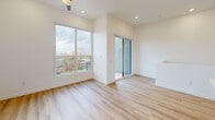 Located at 31902 North Valley Parkway in Phoenix, Arizona, this modern two-story home offers 3 bedrooms and 2 bathrooms across two well-appointed floors. The lower level serves as an inviting entry point, while the upper floor houses the majority of the living space, including all bedrooms, bathrooms, kitchen, and hallway.

The kitchen is a standout feature, showcasing a clean, contemporary design with two-tone cabinetry — warm natural wood lower cabinets paired with crisp white upper cabinets — complemented by a white subway tile backsplash, quartz countertops, stainless steel appliances, and a large island with pendant lighting. Light hardwood flooring flows throughout the home, enhancing its bright, airy atmosphere.

The spacious primary bedroom features a ceiling fan, large windows with community views, and a sliding glass door leading to a private balcony with decorative block railing. A generous walk-in closet with built-in shelving and hanging rods provides ample storage. The en-suite bathroom offers a glass-enclosed walk-in shower, wood-toned vanity, and a small window for natural light.

The second bathroom includes a full tub-shower combo, matching vanity, and black matte hardware accents. The additional bedrooms are bright and well-sized, featuring hardwood floors and clean white walls. Black hardware details throughout provide a cohesive modern touch.