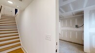 Located at 2701 Rozzelles Ferry Road in Charlotte, NC, this modern multi-story home spans four floors and offers a well-organized layout with 3 bedrooms, 4 full bathrooms, and a thoughtful array of support spaces including a laundry room, pantry, and six closets. The ground level features a spacious garage with a panel ceiling, automatic opener, natural light from a side window, and interior access. The main living floor is the heart of the home, showcasing warm hardwood-style flooring throughout. The kitchen stands out with crisp white shaker cabinetry reaching to the ceiling, sleek quartz countertops, stainless steel appliances including a side-by-side refrigerator and range, and a central island. Bright, light-filled living spaces feature recessed lighting and generous windows with transoms that invite abundant natural light. Bathrooms are finished with white vanities, quartz counters, and matte black hardware accents for a contemporary touch. Bedrooms are carpeted for comfort, with the upper-floor primary suite featuring vaulted ceilings, a ceiling fan, a walk-in closet with built-in rods, and an en-suite bath. Connecting all levels are wood-treaded staircases set against clean white walls, reinforcing the home's fresh, modern aesthetic throughout.