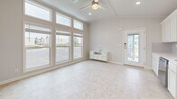 Located at 1009 Big Constellation Way in San Marcos, TX, this efficient single-story home offers a well-designed layout across one bedroom, one bathroom, and a combined living and kitchen space. The exterior features charming sage-green board-and-batten siding, a covered front porch with warm wood-tone decking and black iron railings, and stair access — creating an inviting first impression within a landscaped community setting.

Inside, the main living area stands out with soaring vaulted ceilings, a ceiling fan, and an expansive wall of large-pane windows that flood the space with natural light and provide open views of the surrounding neighborhood. Light-toned tile flooring runs throughout, contributing to a clean, airy aesthetic.

The kitchen is well-appointed with crisp white shaker cabinets, a subway tile backsplash, light countertops, a stainless steel sink, and a full suite of stainless steel appliances including a range, over-the-range microwave, and dishwasher.

The bedroom features a vaulted ceiling, a ceiling fan, a natural-light window, and continues the consistent tile flooring. The bathroom is efficiently designed with white cabinetry, a glass-enclosed walk-in shower with tile surround, and a window for ventilation. This home offers a practical and modern living experience in a well-maintained community.