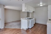 Located at 137 N Orange Ave in Brea, California, this single-floor unit offers a functional and well-organized layout designed for comfortable everyday living. The kitchen is a standout feature, equipped with white cabinetry, tile countertops, a gas cooktop on a peninsula island with overhead ventilation, a dishwasher, and a sink — all set on hardwood-style flooring that adds warmth to the space. The kitchen flows openly into the living area, which is finished with plush carpet and features a sliding glass door fitted with vertical blinds, allowing natural light to fill the room while providing access to outdoor views. The bedrooms continue the carpeted aesthetic and include closets with built-in shelving, as well as sliding glass doors that bring in additional daylight. Both bathrooms are thoughtfully designed with accessibility in mind, featuring grab bars throughout. One bathroom includes a combination tub and shower with wood-style flooring, while the second offers a roll-in tile shower with a mosaic-tiled floor and light ceramic tile underfoot. Throughout the unit, textured ceilings, neutral wall tones, and consistent finishes create a cohesive and practical living environment well-suited for a range of residents.