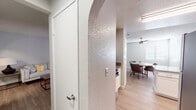 This single-floor residence offers a thoughtfully designed layout connecting living, dining, and kitchen areas in a cohesive, open flow. Consistent light wood-style flooring runs throughout the space, complemented by neutral gray and white walls that create a clean, modern aesthetic. Textured ceilings add subtle character across all rooms.

The kitchen is well-equipped with white shaker cabinetry, granite-style countertops, a stainless steel dishwasher, and a double-basin sink. A pass-through window opens toward the dining area, enhancing the sense of connectivity. The dining space accommodates a round table beneath a ceiling fan, with a window providing natural light.

The primary bedroom is generously sized with a walk-in closet and direct access to an en-suite bathroom. The en-suite features a granite-topped vanity with white cabinetry, a soaking tub, and a bright vanity light fixture. The second bedroom is comfortably proportioned with a window and easy access to the second full bathroom, which includes a granite vanity, white cabinetry, and matching finishes consistent with the rest of the home.

Arched interior doorways provide a distinctive architectural detail, adding visual interest throughout the hallways. Natural light filters in through window blinds in each room, contributing to the bright, welcoming ambiance of this well-maintained residence.